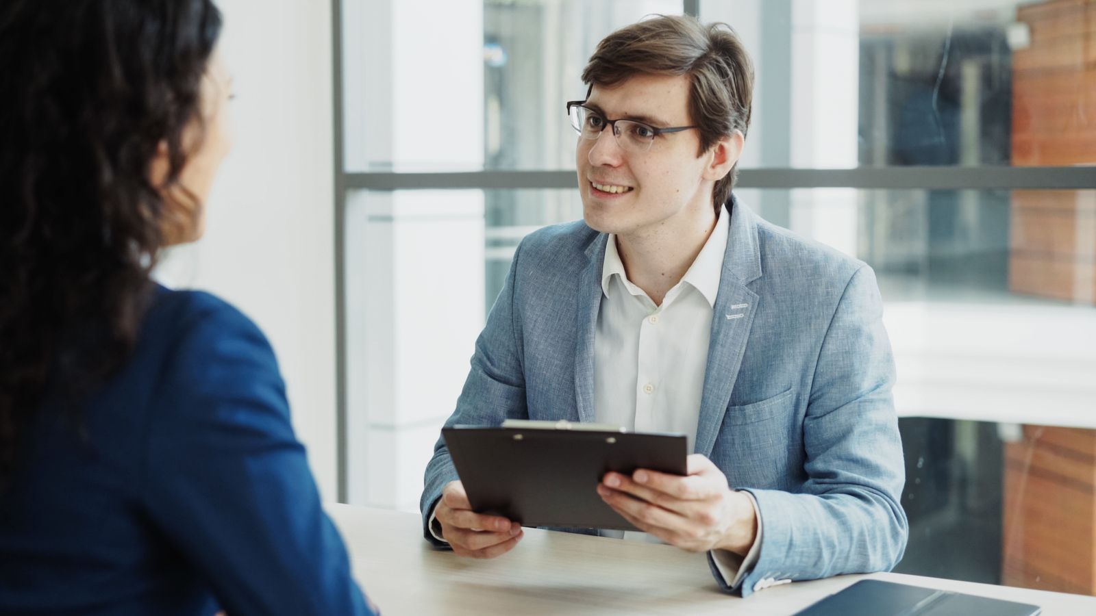 Two professionals talking across a table in a naturally lit office